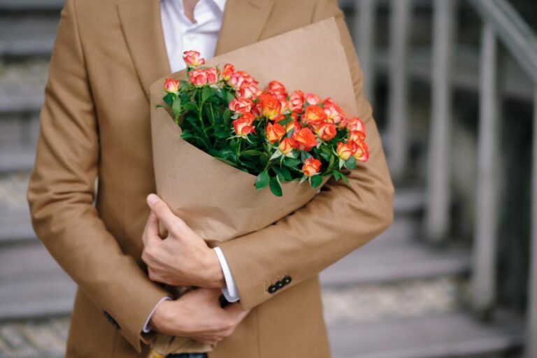 A man embracing a flower bouquet folded nicely with craft paper.